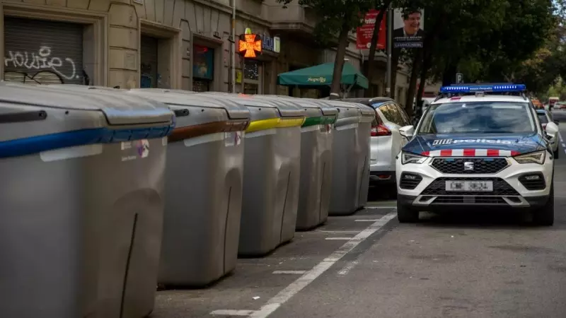 Un coche de la Policía aguarda junto a un contenedor del centro de Barcelona, a 29 de noviembre de 2022.