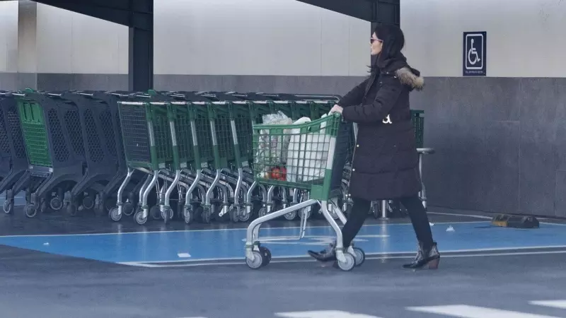 Una mujer sale de un supermercado con un carro de la compra, a 27 de diciembre de 202