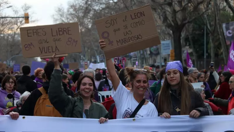 Tres manifestants mostren pancartes a la marxa feminista del 8-M a Barcelona.