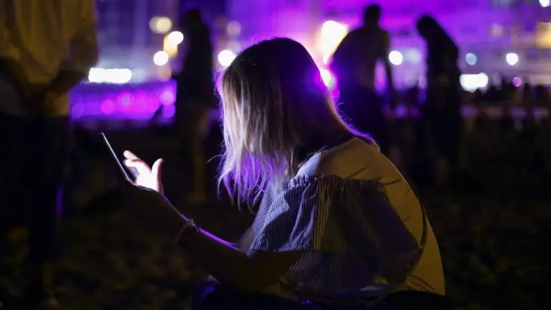 Imagen de archivo de una mujer mientras utiliza su teléfono móvil en una fiesta, a 14 de agosto de 2022.