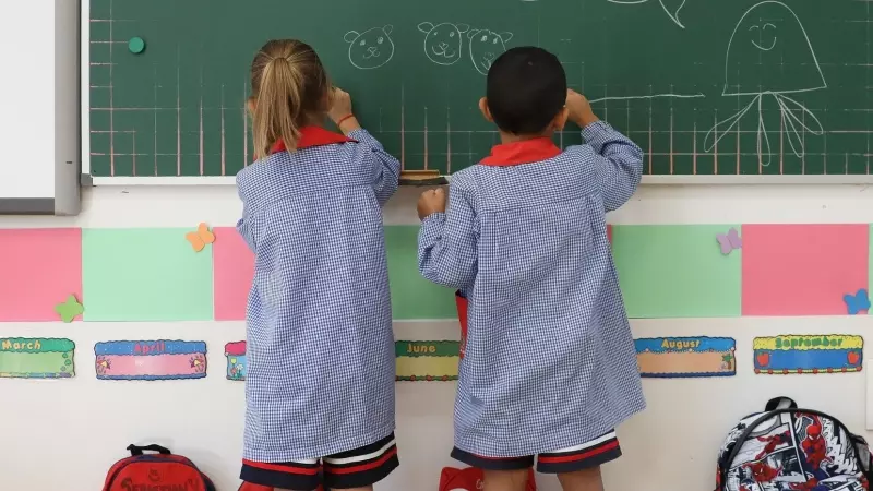 Dos niños pintan en una pizarra el día de inicio del curso en el colegio de la Alameda de Osuna, a 5 de septiembre de 2022, en Madrid (España)