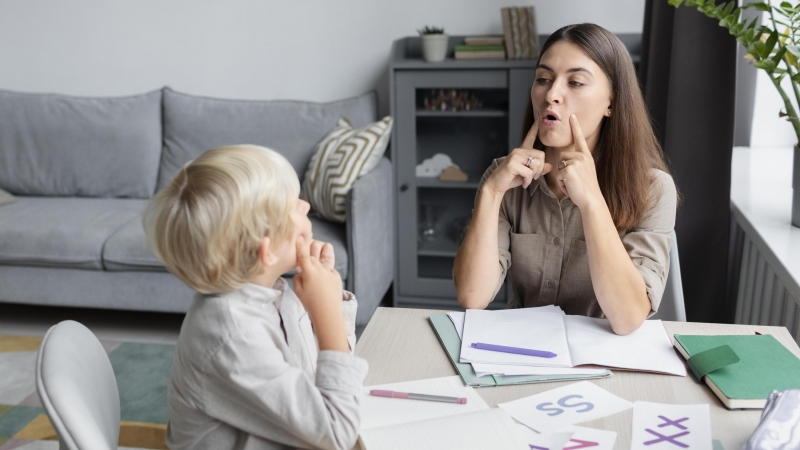 Una logopeda hace terapia del habla con un niño.