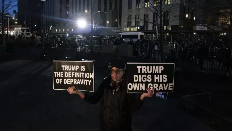 Una persona sostiene carteles contra Trump frente la Corte Penal de Nueva York tras la imputación del exmandatario.
