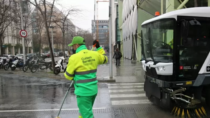 Un treballador netejant a la superilla del Poblenou de Barcelona, juntament amb una de les màquines de la nova flota de vehicles.