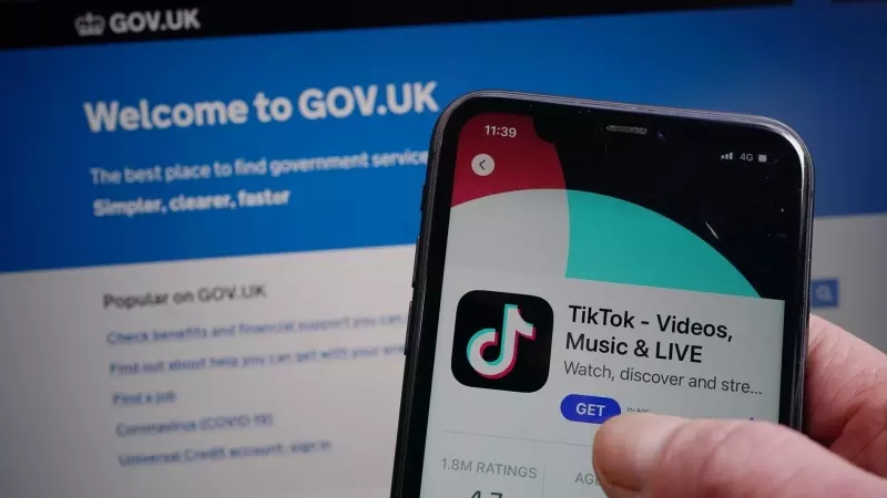 Un usuario se descarga TikTok en su teléfono móvil mientras consulta la página web del Gobierno de Reino Unido.