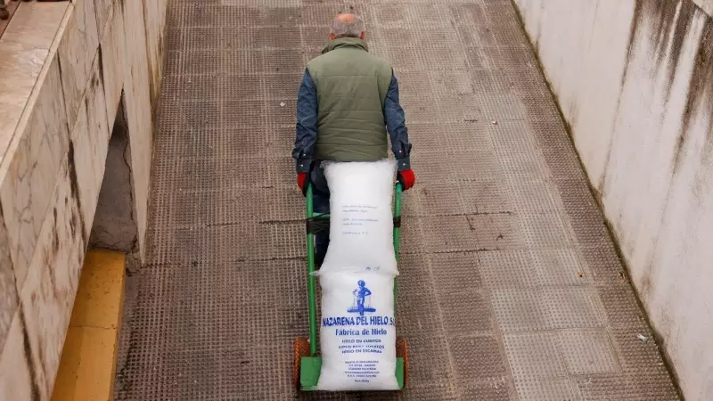 Untrabajador traslada una carretilla con un saco de hielo, en Ronda (Málaga). REUTERS/Jon Nazca