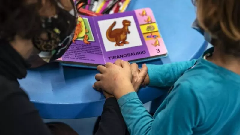 Dos niños en una guardería mirando un libro infantil.
