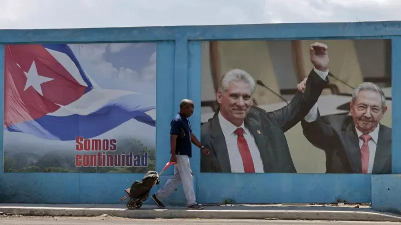 Un hombre camina frente a un fotografía de Miguel Díaz-Canel junto a Raúl Castro, en La Habana (Cuba).