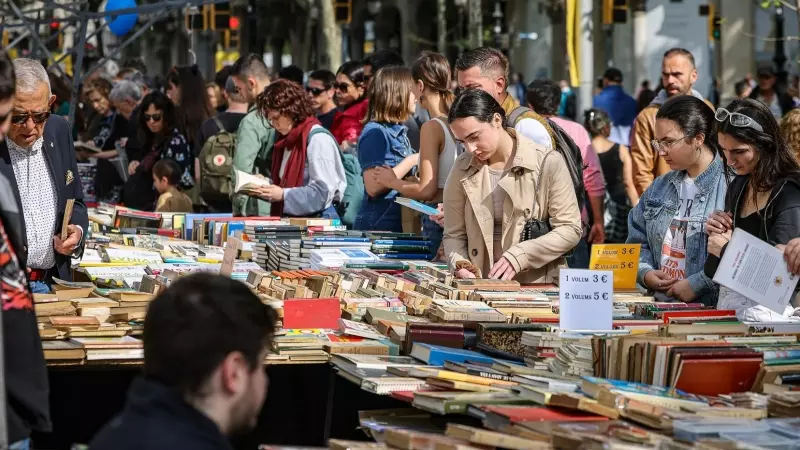 Gent passejant i mirant llibres per les parades de la superilla literària per Sant Jordi a Barcelona.