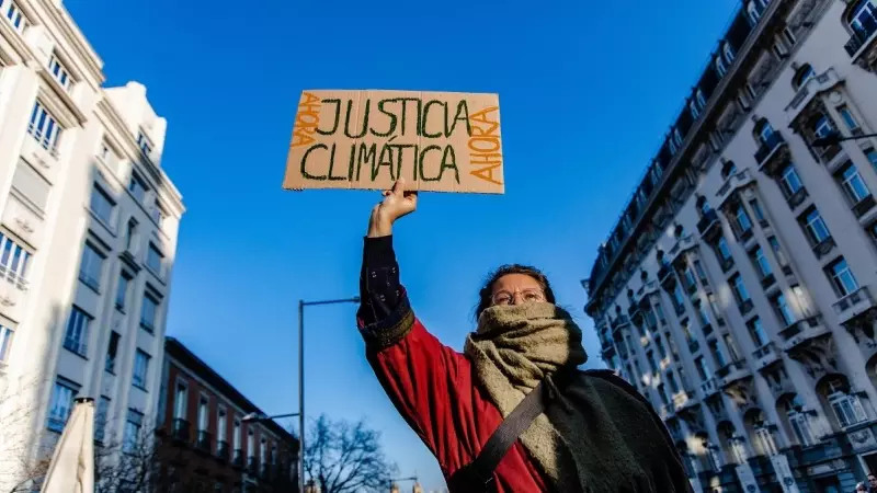 Una mujer sujeta una pancarta durante una manifestación del movimiento ‘Juventud por el Clima’, frente al Congreso de los Diputados, a 3 de marzo de 2023, en Madrid.