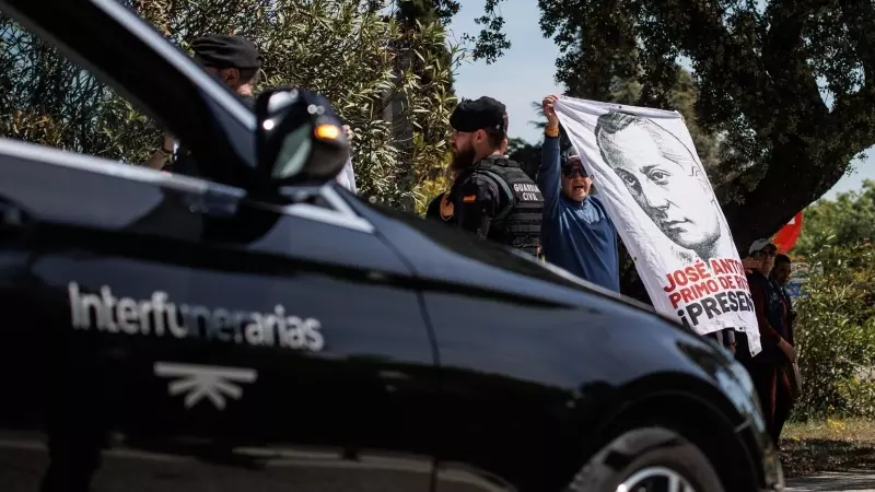 El coche fúnebre con los restos de José Antonio Primo de Rivera, salen de la basílica del Valle de Cuelgamuros, mientras simpatizantes de la falange sujetan una tela con su rostro, a 24 de abril de 2023, en San Lorenzo de El Escorial, Madrid