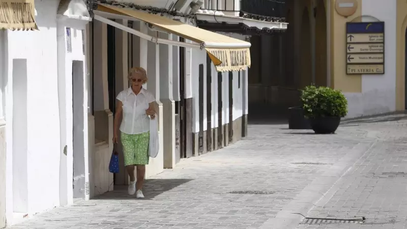 Una mujer intenta caminar por la sombra de los toldos por la calle debido a las altas temperaturas que se están registrando inusuales para el mes de abril, este viernes en Sevilla.