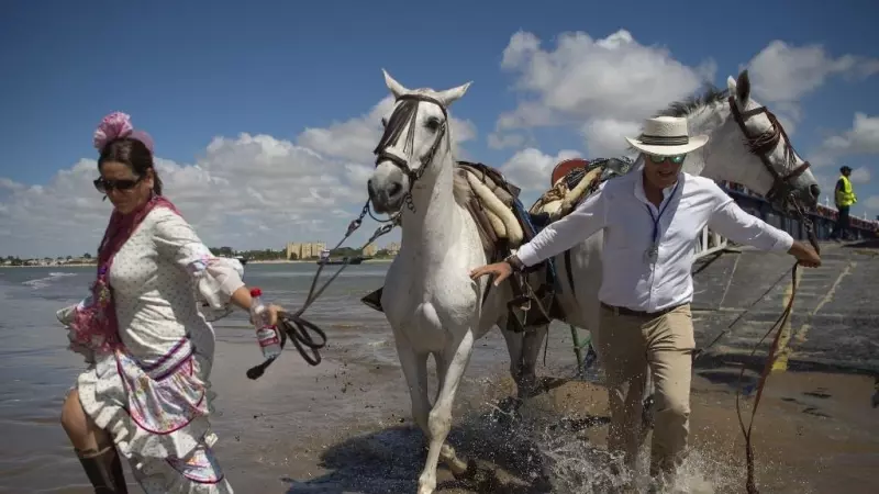 Los peregrinos cruzan el río Guadalquivir en ruta hacia el santuario de El Rocío en el parque nacional de Doñana durante la peregrinación anual de El Rocío.