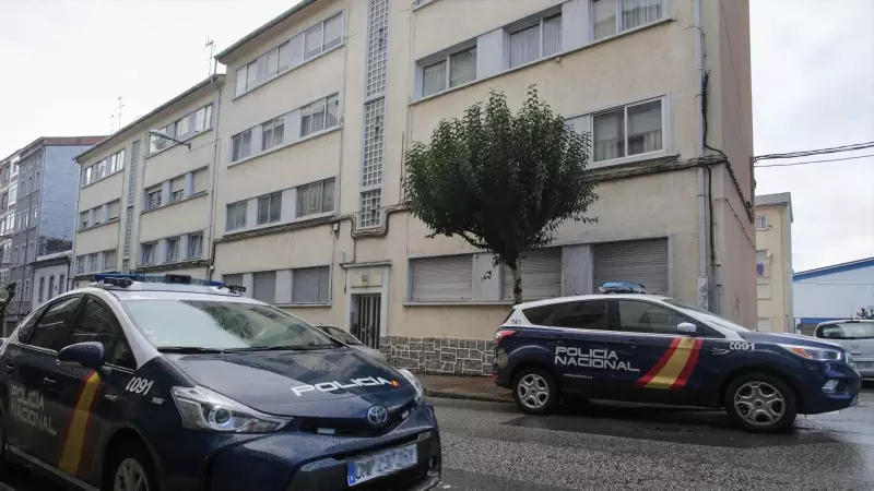 Dos vehículos de Policía Nacional aparcados frente a unos edificios.