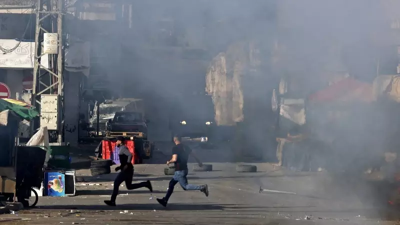 Los palestinos corren para ponerse a cubierto de los vehículos militares israelíes en medio de una redada en la ciudad ocupada de Nablus, en Cisjordania, el 14 de mayo de 2023