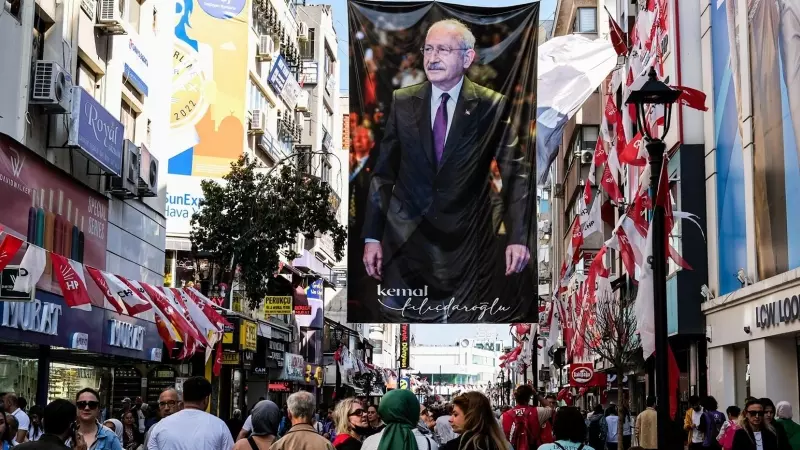 Gente en una calle de Izmir camina debajo de un poster de Kemal Kiliçdaroglu.