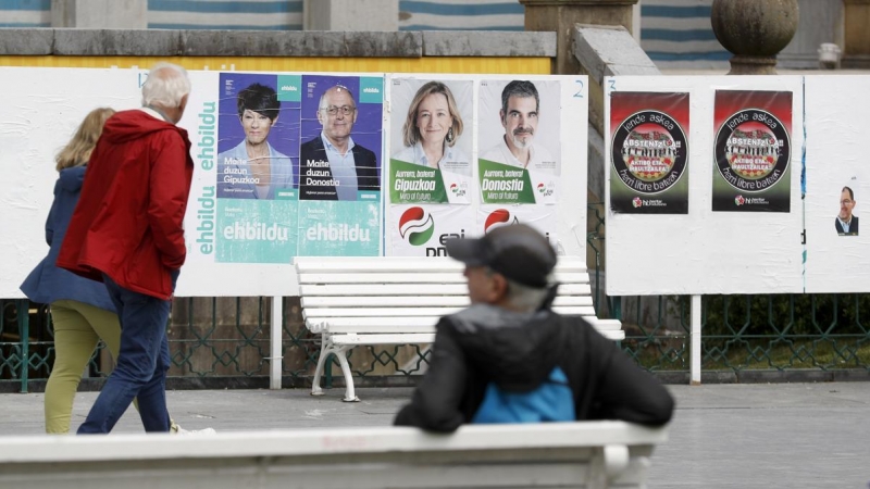 Unos ciudadanos observan varios carteles electorales este martes en San Sebastián, a 16 de mayo de 2023.