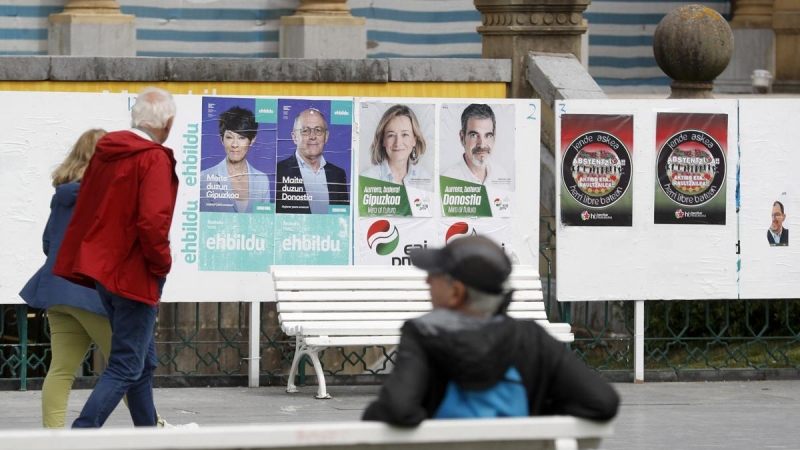 Unos ciudadanos observan varios carteles electorales este martes en San Sebastián, a 16 de mayo de 2023.