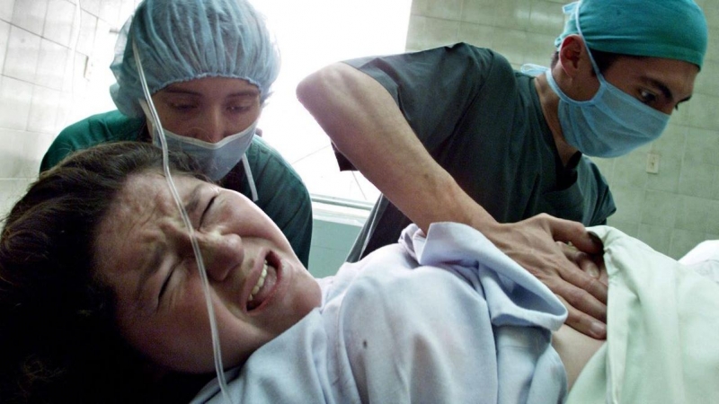 Imagen de archivo de una mujer de parto auxiliada por dos enfermeras en la maternidad de Quito, a 27 de junio de 2003.