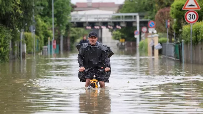 Un hombre monta en bicicleta en mitad de las inundaciones provocadas por las lluvias torrenciales de mayo en Emilia-Romagna, en Italia.