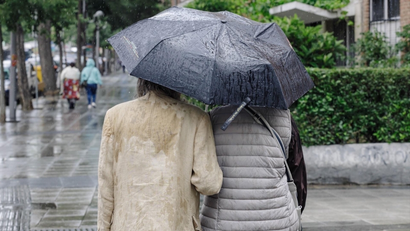 Dos personas con un paraguas pasean por Madrid, a 23 de mayo de 2023.