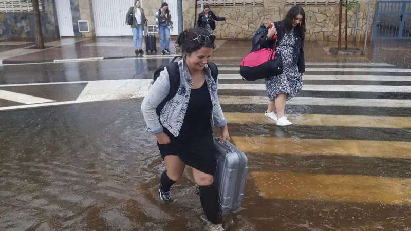 Varias personas cruzan una calle inundada cuando el episodio de lluvias torrenciales ha dejado un registro histórico de 198 litros por metro cuadrado esta madrugada en la ciudad de Castelló.