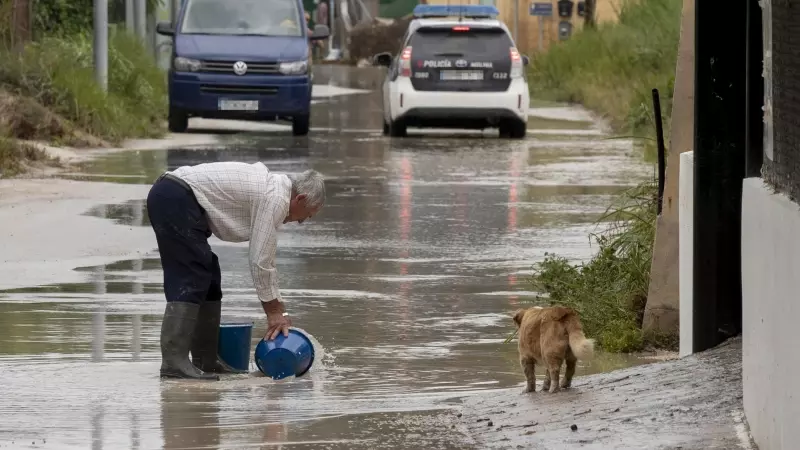 Un hombre retira agua de la calle con dos cubos, este viernes 26 de mayo de 2023, en el camino de la huerta de abajo en Molina de Segura.