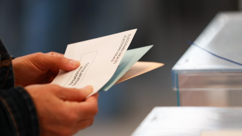 Una persona sostiene papeletas electorales frente a las urnas, a 28 de mayo de 2023