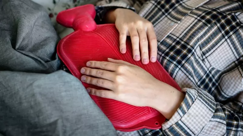 Una mujer sostiene una bolsa de agua sobre su abdomen.