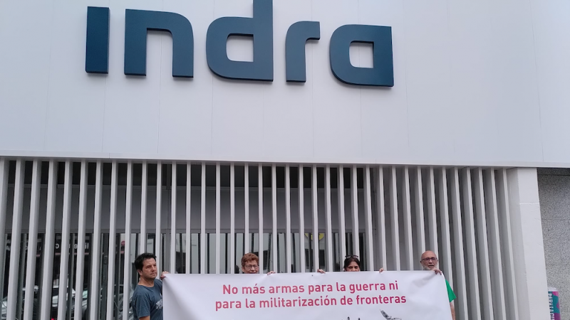 Activistas antimilitaristas despliegan una pancarta delante de la sede de Indra, antes de la Junta de Accionistas de junio de 2022