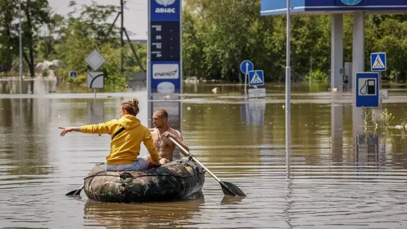 Los residentes locales navegan en un bote en una calle durante una evacuación de un área inundada después de que la represa Nova Kakhovka se rompiera en Kherson.