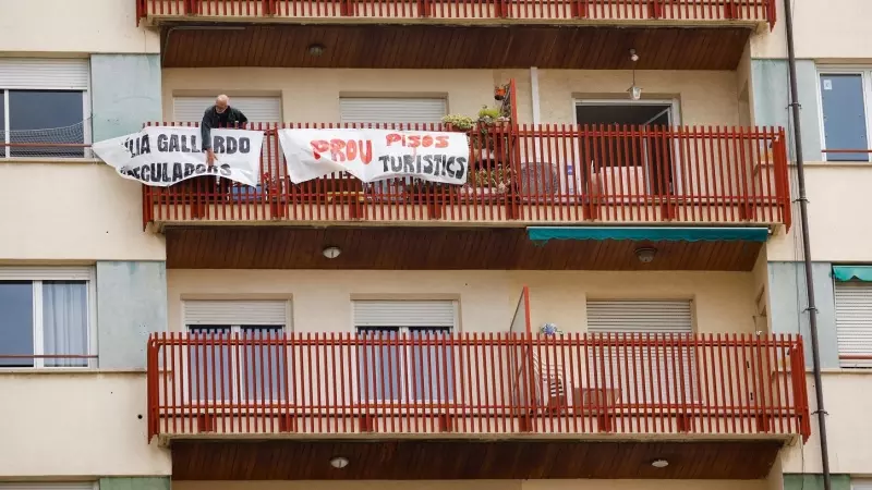 Un hombre coloca una pancarta en el balcón de su casa en protesta por los pisos turísticos del edificio en el que vive, en el barrio de Sants en Barcelona. La pancarta dice 'No más pisos turísticos'. REUTERS/Albert Gea