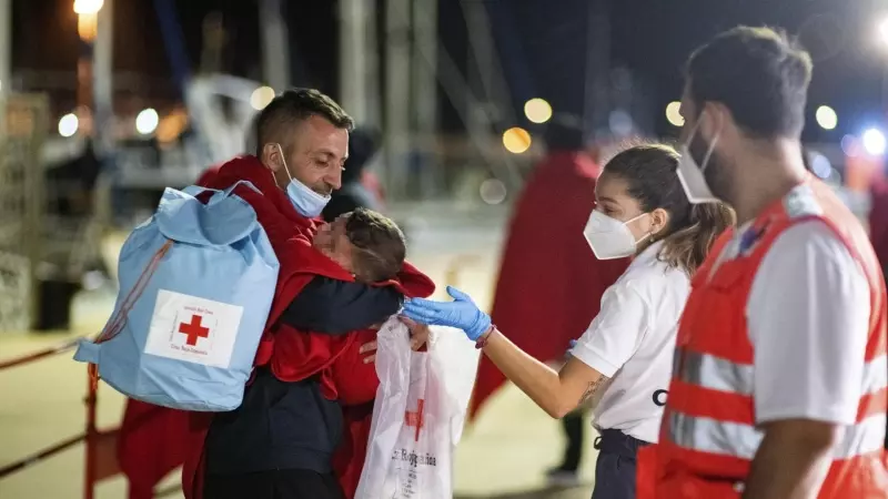 Un hombre acuna en la noche del martes su bebé, de siete meses, en el muelle de Gran Tarajal (Fuerteventura) tras haber sido rescatados.
