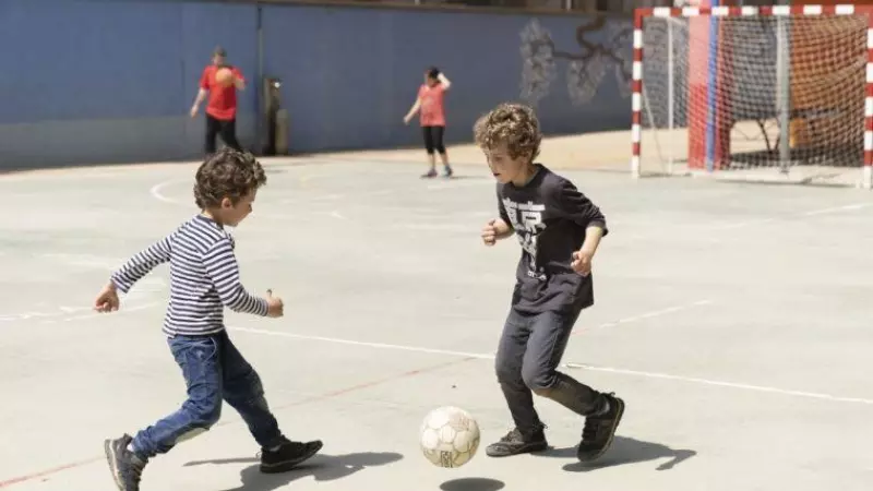 Dos niños jugando a pelota en el patio de un centro escolar de Barcelona.