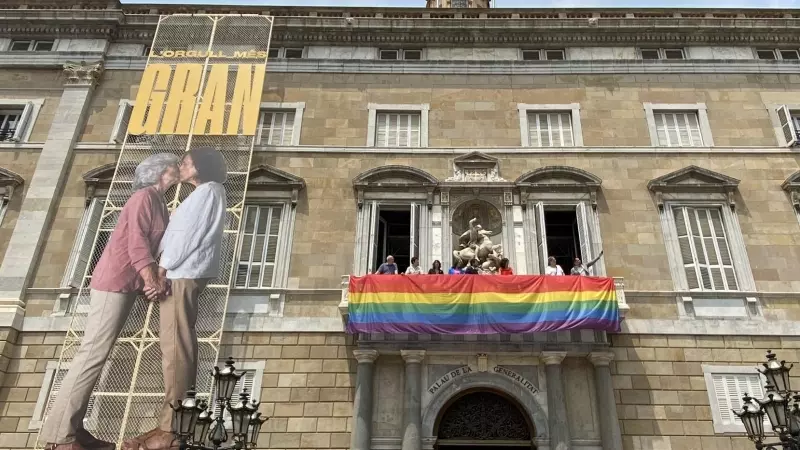 Desplegament de la lona amb la bandera LGTBI a la façana del Palau de la Generalitat.