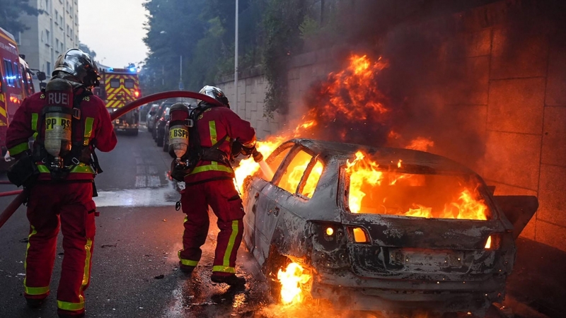 Los bomberos extinguen el fuego en un coche en llamas tras los disturbios en el distrito de Nanterre