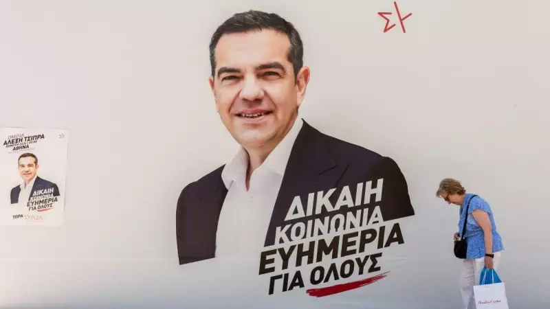 Una mujer pasa por delante de un puesto de campaña de Syriza con una foto del líder del partido Alexis Tsipras en el centro, a 25 de junio de 2023, en Atenas.