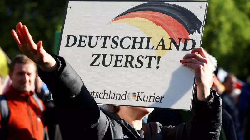 Un seguidor de la formación ultra alemana AfD sujeta una pancarta con el lema 'Alemanes primero' y realiza el saludo fascista, en Berlín, a 8 de octubre de 2022.
