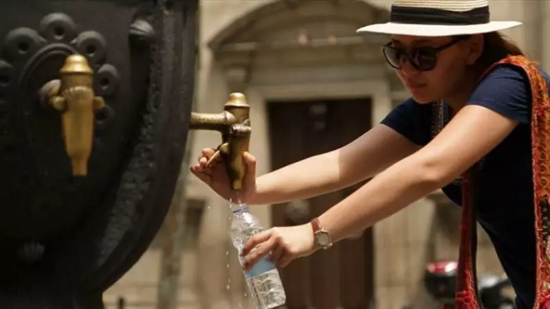 07/2023 - Una mujer llenando una botella en una fuente de agua de Barcelona.