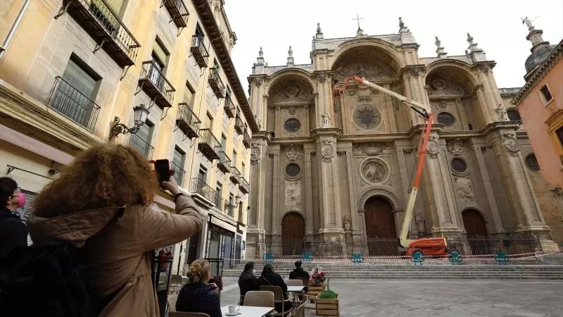 Varios operarios, subido a una grúa , revisan la fachada de la Catedral de Granada. Archivo.