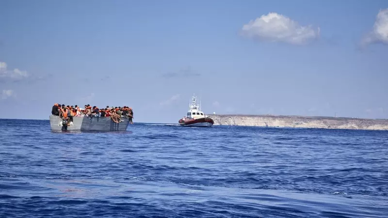 Foto de archivo, patera donde viajan migrantes y una patrullera de la Guardia Costera de Lampedusa