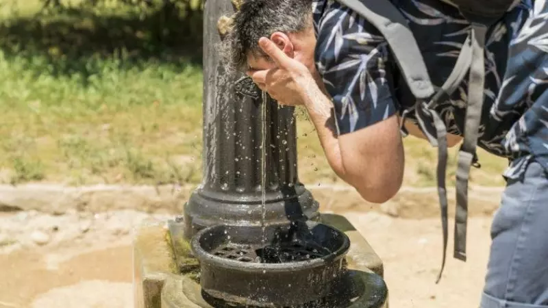 Una persona se remoja en una fuente pública de Barcelona para hacer frente al fuerte calor.