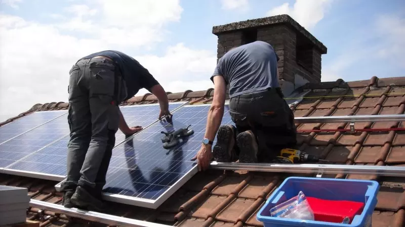 Dos instaladores colocan placas solares en el edificio de una vivienda, en una imagen de archivo
