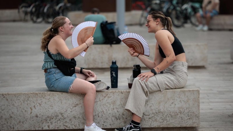 31/07/2023.- Dos jóvenes combaten el calor con sendos abanicos en este último día de julio en el País Valencià.