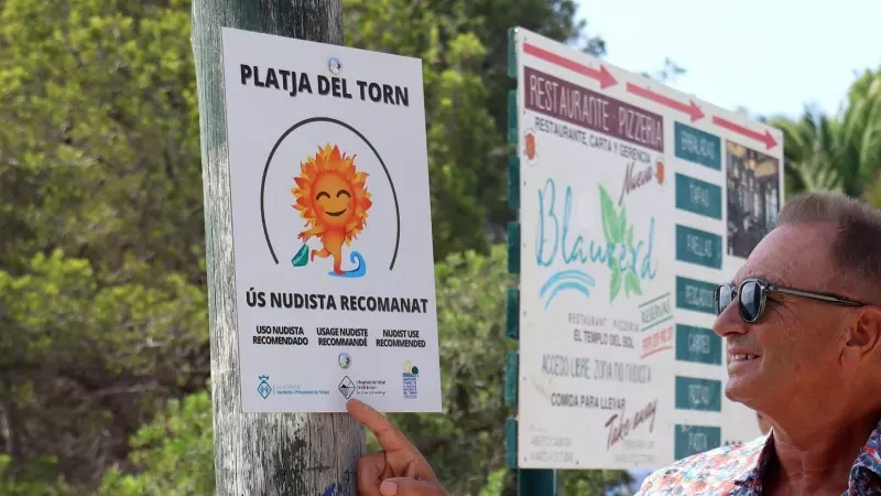 El president de l'Associació d'Amics de la Platja Naturista del Torn senyalant un dels cartells informatius recentment col·locats per l'Ajuntament de Vandellòs i l'Hospitalet de l'Infant.