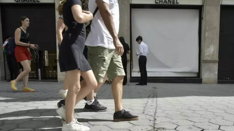 Varias personas caminan frente al escaparate de la tienda de Chanel que ha sufrido esta madrugada un intento de robo, a 7 de agosto de 2023, en Barcelona, Catalunya (España).