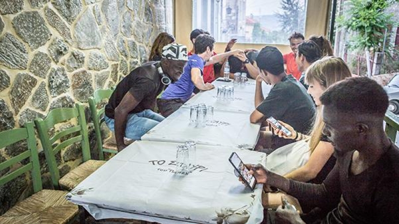 Algunas personas en movimiento de Lesbos se sientan en una de las tabernas centrales de Agiasos, Stavi Tavern, junto con algunos voluntarios de la asociación Yoga y Deportes con Refugiados, después del Agiasos Mountain Trail. En la foto, primero a la dere
