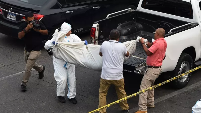 El personal de medicina forense traslada el cuerpo de uno de los jóvenes asesinados a tiros por pandilleros en las inmediaciones de un centro comercial en Tegucigalpa el 26 de abril de 2023.