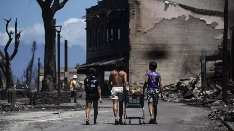 11/08/2023 - Tres residentes empujan un carrito en medio de las ruinas provocadas por el incendio forestal que arrasó la ciudad hasta la costa y el puerto en Hawái, a 11 de agosto de 2023.
