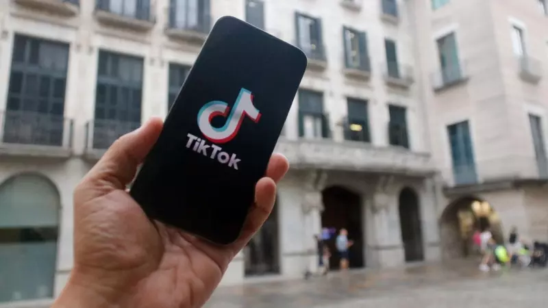 Un mòbil amb el logotip de TikTok davant de l'Ajuntament de Girona
